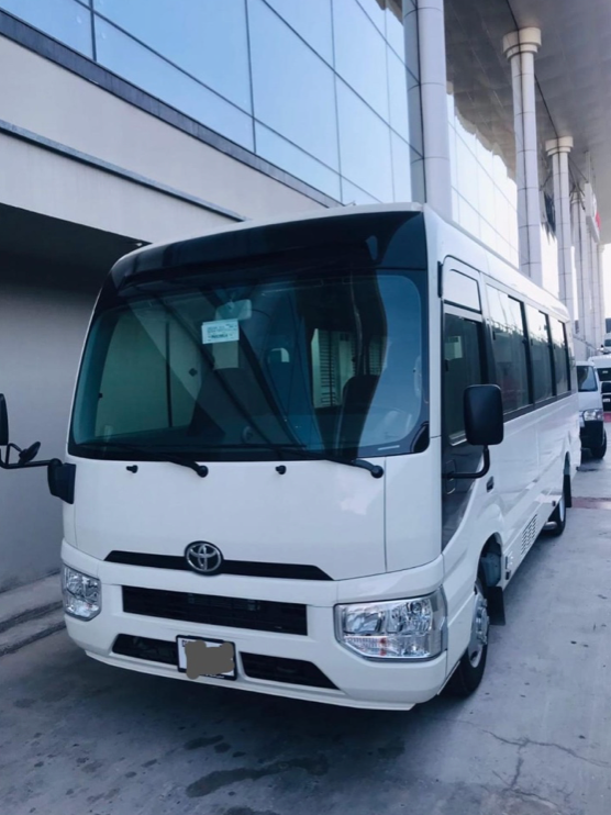 White Luxury Coach Bus – SSM Chauffeurs White luxury coach bus parked beside a modern building