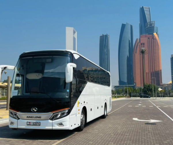 Premium Coach Bus UAE – SSM Chauffeurs Luxury coach bus parked against UAE city skyline
